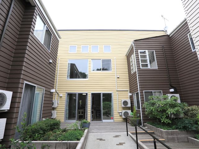 外観のエントランス 交流の場としても役立つサンルーム 温かみのある色使いの建物エントランスは、来訪者を暖かく迎え入れます。バリアフリー設計で、どなたでも安心して通れる造りになっています。