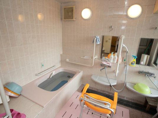 明るく清潔な浴室である。壁の随所に手すりと緊急用のブザーが設置されており、洗体場にはシャワーチェアや洗面器が用意されている。