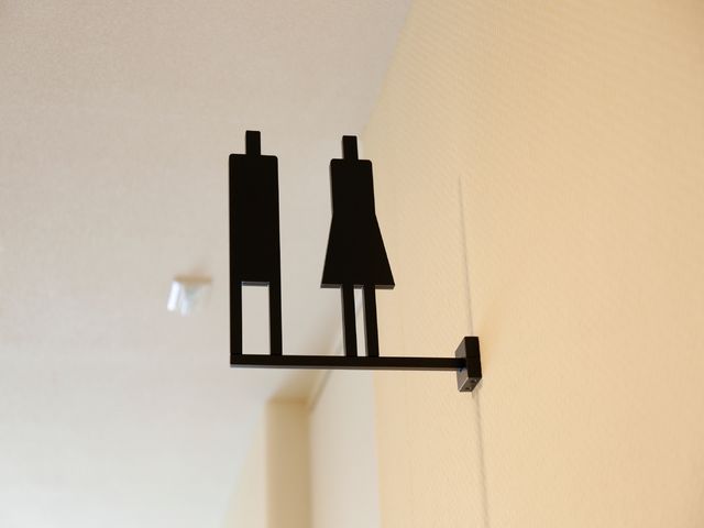 洗練されたウォールデコレーション 共用トイレの表示札 モダンなデザインのウォールアートが設えられた、おしゃれな雰囲気のエントランスです。お迎えする際も心地よい空間で待機できます。