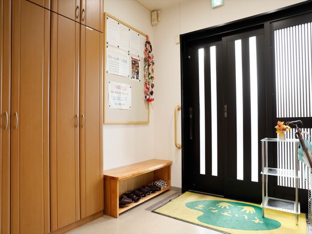 明るく広々としたエントランス 玄関 木目調の家具が落ち着いた雰囲気のあるエントランスです。明るい掲示板と広い靴箱が、ご来訪者の快適な出迎えを演出しています。