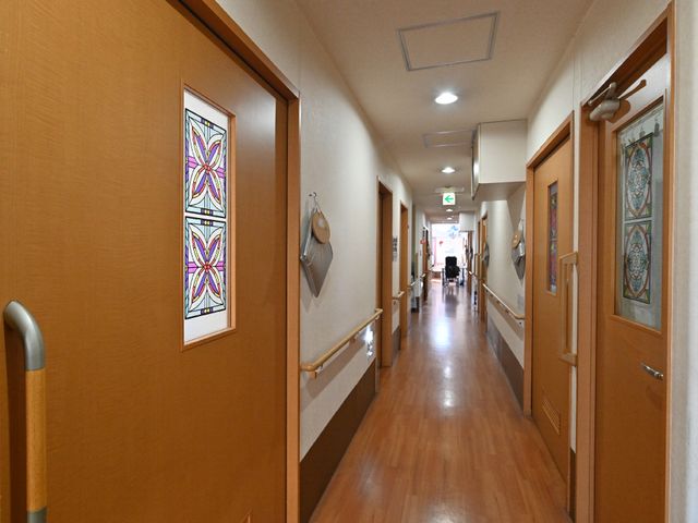 明るい廊下と装飾窓 廊下 清潔感のある温かみのある廊下は、彩り豊かな装飾窓で明るい印象を与えています。手すりの整った安心設計で、静かな環境が広がっています。