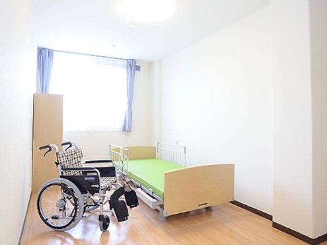 シンプルな居室と車椅子 明るく清潔感のある居室です。車椅子を備え、バリアフリーな環境が整っていることがうかがえます。