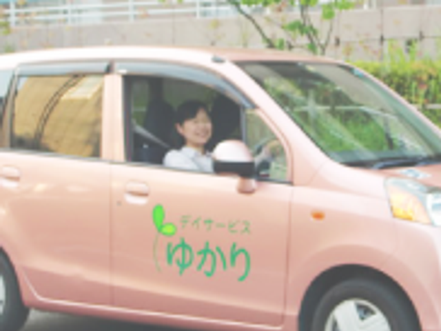 車での送迎の様子 スタッフイメージ 笑顔で運転するスタッフが見られます。送迎サービスについての理解が深まります。