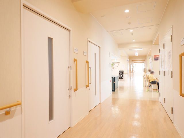 明るい廊下 通路 手すり付きのきれいな通路を備え、快適に過ごすことができる空間です。ゆったりとした椅子で休憩をとる方も見えます。