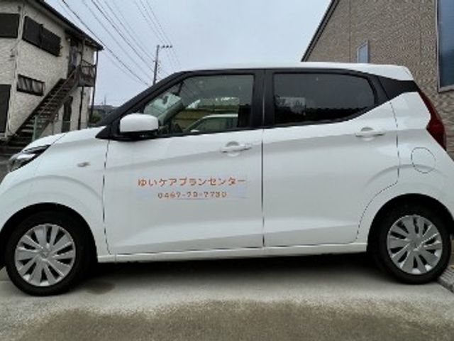 送迎車の外観 外観   白い送迎車が停まっており、施設の移動支援の様子が伝わります。乗り降りしやすい車両を使う職場をイメージできます。