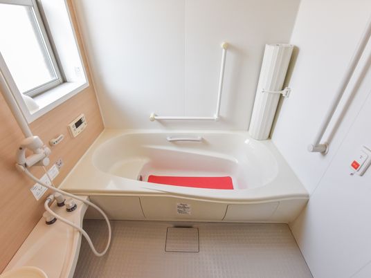 清潔感のある浴室には複数の手すりが設けられている。シャワーもあり、洗面台をおくスペースも用意されている。