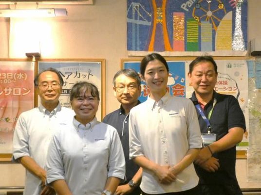 スタッフ5人の集合で案内板の前  