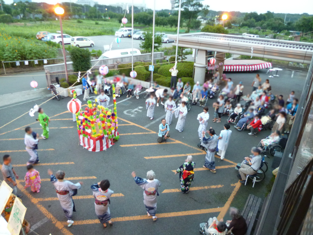 祭りの様子が伺える庭 庭 庭では、賑やかな祭りが行われており、多くの入居者の方々が楽しそうな様子です。