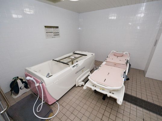 白い壁の広間に配置された機械浴室とピンクのストレッチャー