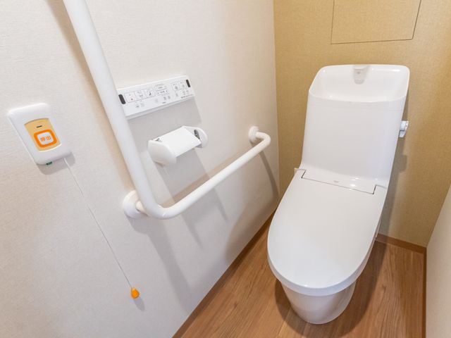 手すり付きトイレ トイレ   手すりが設置された明るいトイレです。安全に使いやすい配慮が感じられ、働く環境の確認にも役立ちます。