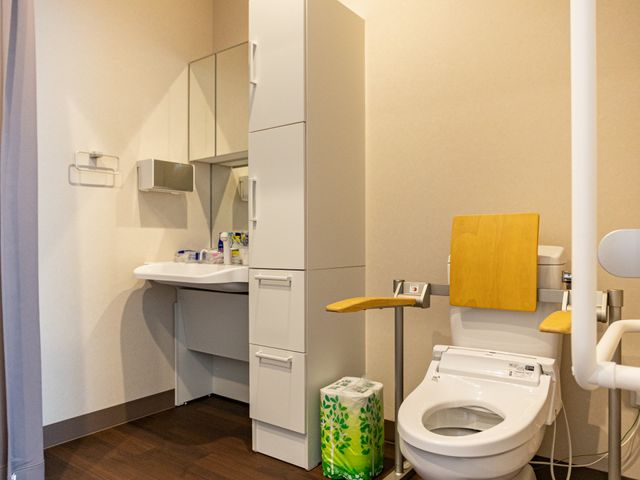 手すり付きトイレ トイレ   手すりや洗面台が備わった、使いやすいトイレです。木目調の床で、落ち着いた雰囲気です。