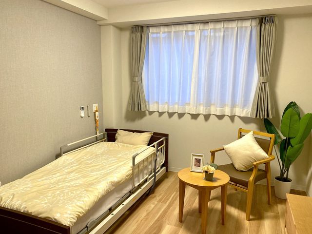 明るい居室の様子 居室   大きな窓からやわらかな光が入り、落ち着いた雰囲気の居室です。ベッド横に椅子とテーブルがあり、くつろぎやすい空間です。