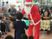 サムネイル サンタクロースの姿の男性が、女の子にプレゼントを渡している様子である。地域の人々との交流を深めながらクリスマス会が行われている。