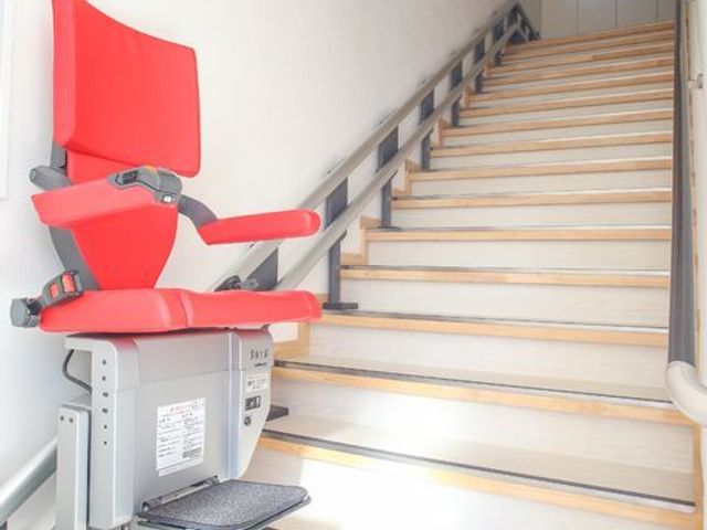 階段昇降機付き廊下 オシャレな補助器具 手すりと階段昇降機が備わった廊下は、どなたでも安全に移動できる設計です。バリアフリーに配慮しており、快適な勤務環境が整っています。