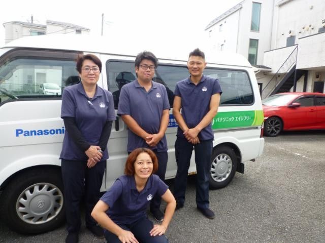 スタッフ集合の屋外 スタッフイメージ   ポロシャツ姿のスタッフ4人が、白い車の前に並んでいます。現場の雰囲気が伝わり、働く様子をイメージしやすいです。