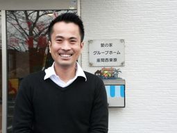 笑顔の男性と施設看板