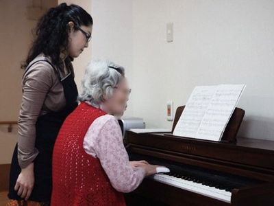 ピアノを弾く女性と支援者