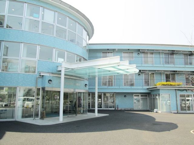 青い外観の施設 外観   曲線を取り入れた青い外壁が印象的な建物です。出入口前に屋根付きのスペースがあり、雨の日の出入りにも配慮されています。