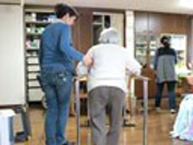 優しいサポートの光景 ラウンジ 和やかな雰囲気の中で、支え合いながら歩行練習を行っています。助け合う姿勢が感じられます。