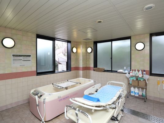 寝たままの状態で入浴できる介護浴槽がある。いろいろな石鹸やシャンプーが置いてある。清潔な浴室である。