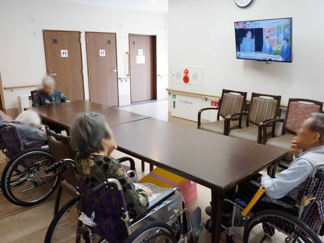 車椅子使用者の食堂 共有スペース 広々としたテーブルが配置された食堂です。入居者の皆さんがテレビを見ながらゆっくりと過ごされています。