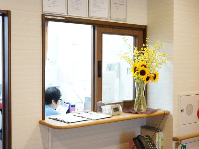 フロントに花飾りとスタッフ 受付窓口 スタッフが業務に集中する快適なフロントです。カウンターに飾られた花が訪れる方を明るく迎えています。