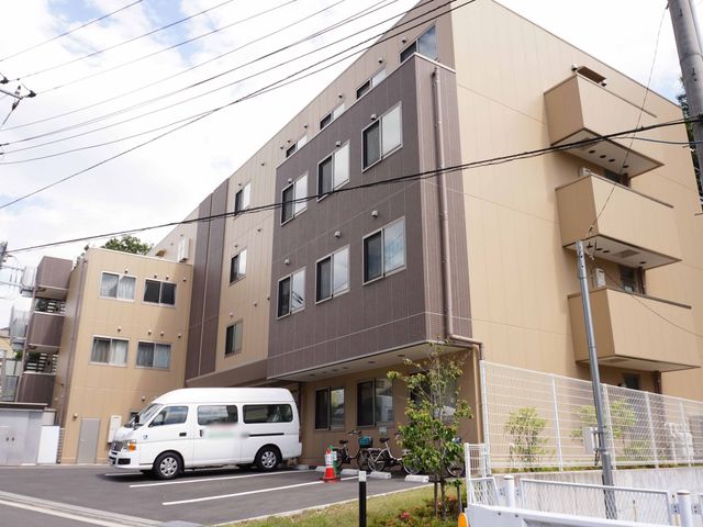 多階層施設の外観 外観 きれいな建物の入口には、スタッフが常駐し、訪れる方を温かく迎えています。落ち着いた色合いの外壁が、地域に調和した印象を与えています。