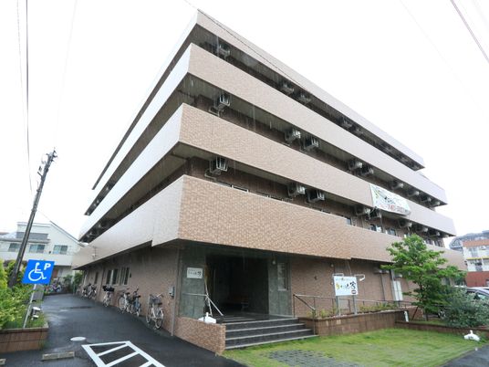 煉瓦造りの3階建て。入口は階段と手摺があり、脇にはスロープが設置されている。車椅子専用の駐車スペースがある。
