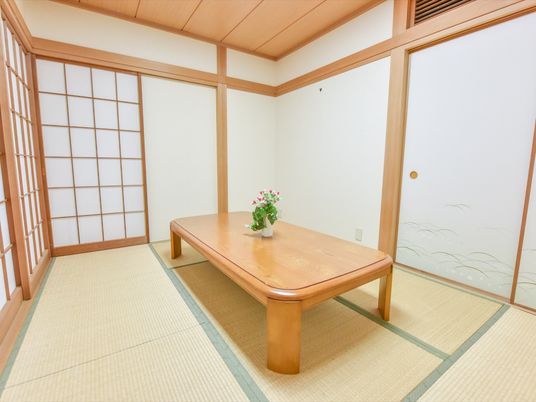 6畳程の畳スペースがある。白い壁や襖、障子が明るく綺麗な本格的な和室。テーブルには花が飾られている。