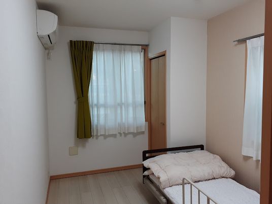 白を基調としたシンプルなお部屋は清潔感がある。エアコンとベッドが設置されており、気持ちよく過ごすことができる。