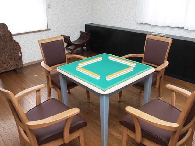 居心地の良いゲームルーム ラウンジ 自然光が入る明るいスペースに、快適な椅子とテーブルが設置されています。リラックスしながらの交流に最適です。