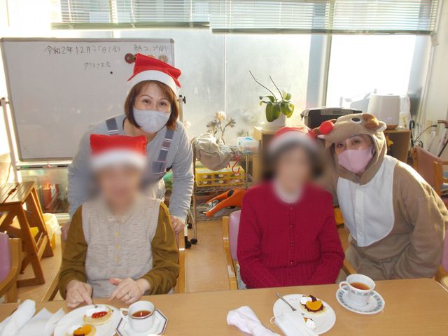 笑顔のホームイベント ダイニングルーム クリスマスイベントで和やかに過ごす利用者とスタッフ。温かいお茶とケーキで交流を深めます。