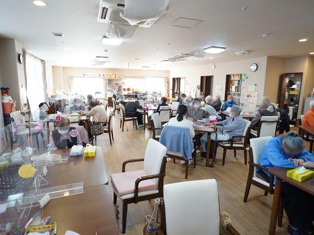 明るい共有スペース 共有スペース 広々とした食堂では、利用者が明るい雰囲気の中で食事や様々な活動を楽しんでいます。それぞれがゆったりとした時間を過ごしている様子が伺えます。