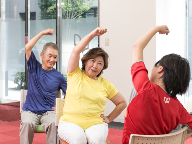 活動する人々リビング 穏やかな表情で運動を楽しむ方々の姿が見られます。それぞれのペースで体を動かし、健康維持に励んでいらっしゃいます。