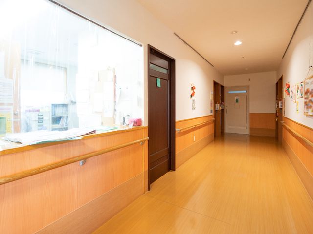 廊下の温かみのある空間 廊下 ゆったりとした廊下は、壁沿いに掲示物が飾られ、温もりを感じる雰囲気が漂います。働くスタッフの活気も感じられます。