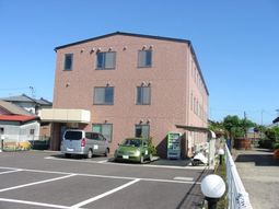 ピンクの外壁の建物と駐車場