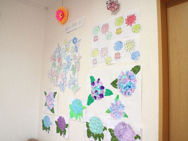 手作りの花紙飾り 作品 手作りの花の紙飾りが壁に飾られ、温かみのある雰囲気を演出しています。クリエイティブな活動が行われる場所です。