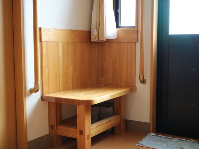木製のベンチと手すり 通路 手すり付きのベンチが備えられた安心感のある空間です。シンプルで清潔感があり、ゆったりとお過ごしいただけます。