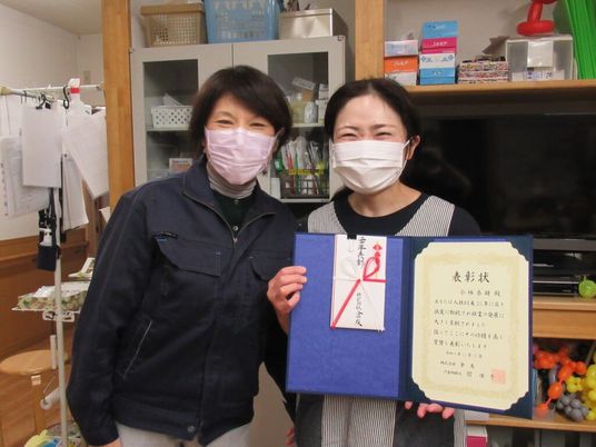 スタッフ2人が表彰状を持つ休憩室  