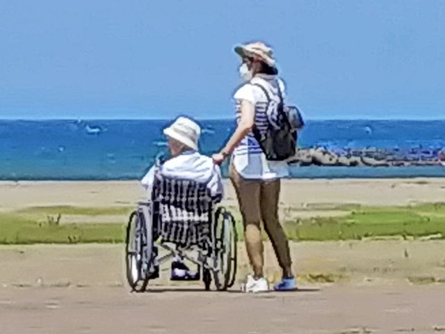 車椅子で海辺を散歩するシーン 庭   開放的な海辺でリラックスしながら、安心して過ごせる環境が整っています。