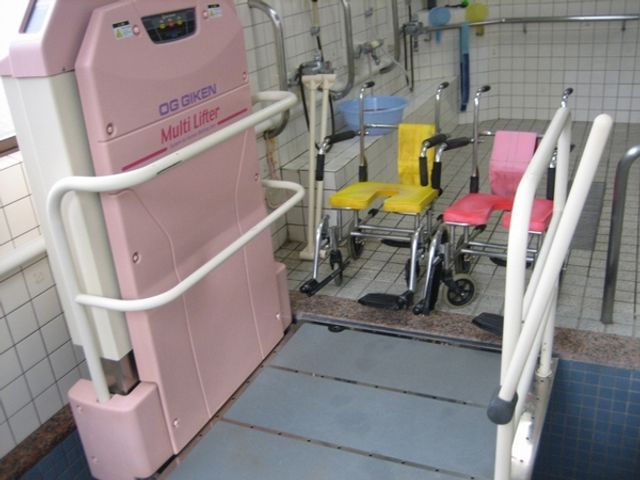 椅子と機械の設置された浴室 浴室 手すり付きのリフターで、安全に入浴サポートが可能です。明るい空間で快適な介助ができます。