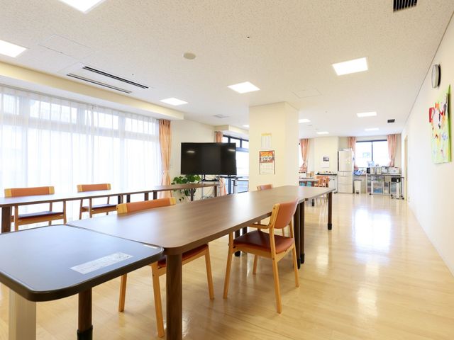 共有スペースの広々とした居室 共有スペース 木目調のテーブルが並ぶ明るく開放的な食堂です。職員とのコミュニケーションを大切にしながら業務をこなせる環境が整っています。