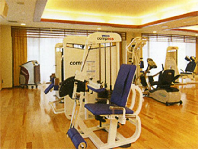 運動機器が並ぶ部屋 機能訓練室 広々とした機能訓練室では、最新の機器を利用して快適にリハビリが行えます。自然光が差し込む明るい空間です。