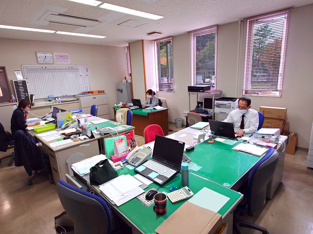 明るい事務室 スタッフイメージ 日差しが入る明るい空間で、スタッフがデスクワークに励んでいます。快適な環境で働けます。