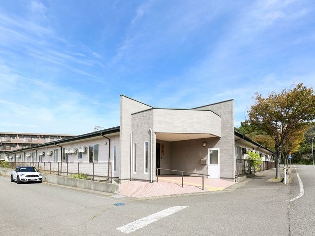 清潔感ある施設外観 外観 広々とした駐車スペースと明るい入り口が迎える、落ち着いた色合いの建物です。