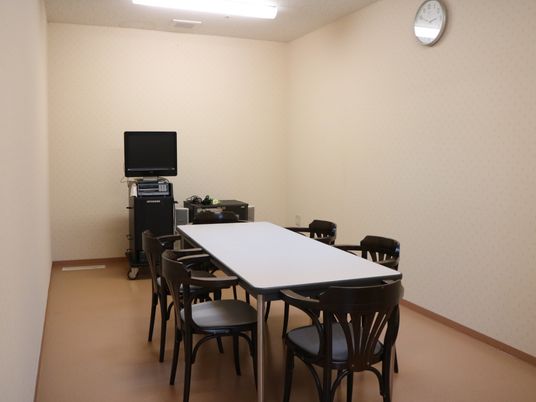 カラオケの設備が設置されている共有スペースである。部屋の中央にはテーブルが置かれ、椅子も備えられている。