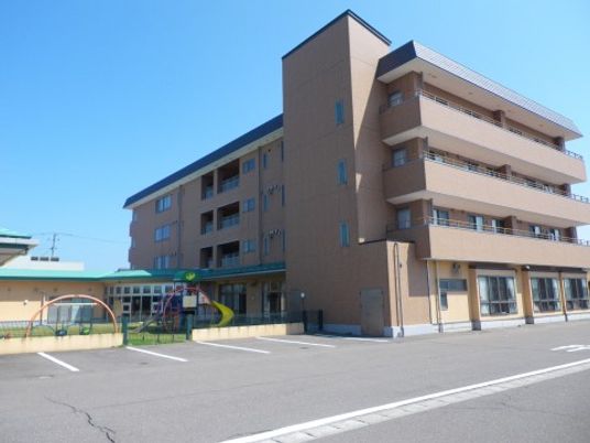 「介護付有料老人ホーム スローライフもんぜん」の外観。落ち着いた色合いの建物。