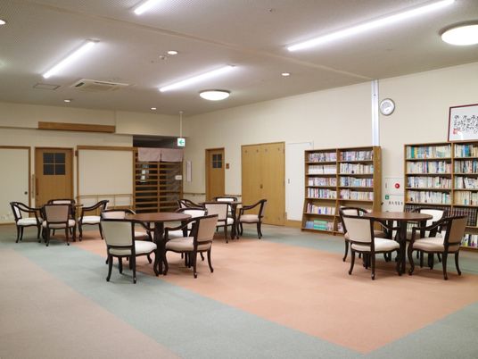 壁に沿って配置された書棚には、びっしりと書物が並んでいる。書棚の前には丸テーブルがあり、背もたれと肘掛けのついた椅子が備わっている。