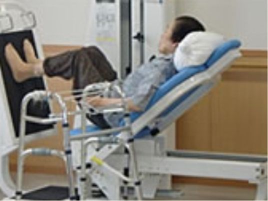 入居者様が運動器具を使って、足の運動をしている様子。筋力の維持と向上のための機能訓練室が施設内にある。