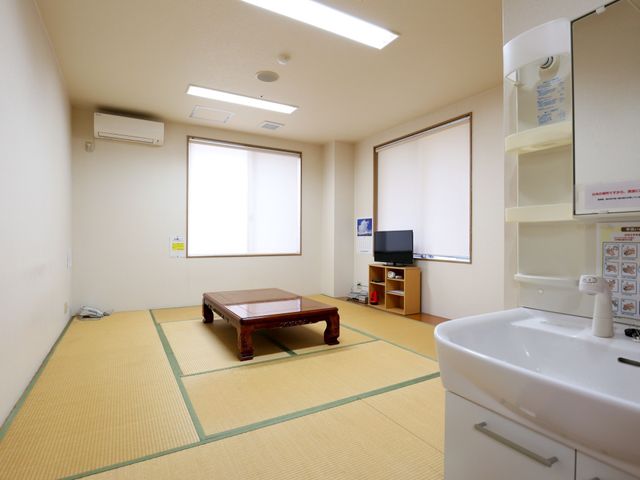 和室の居室 談話室 広々とした和室の部屋で、日本式の座卓が置かれており、ゆったりと過ごせる環境が整っています。手洗い場も備え付けられ、実用性も配慮されています。